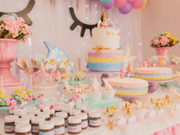 A vibrant unicorn-themed birthday party setup with cakes, cupcakes, and decorations.