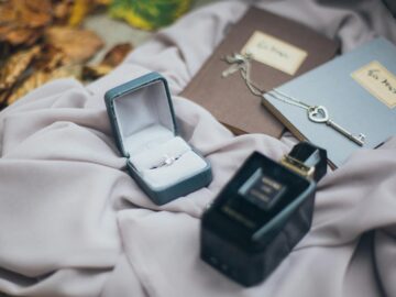 A romantic setup featuring a ring, vintage key, and perfume on soft fabric with autumn leaves.