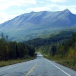 an empty road with mountains in the background