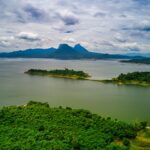 Stunning aerial view of lush green islands against a backdrop of mountains and serene lake in Purwakarta, Indonesia.