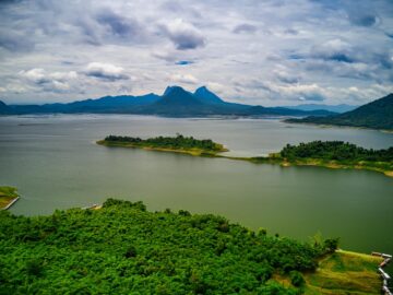 Stunning aerial view of lush green islands against a backdrop of mountains and serene lake in Purwakarta, Indonesia.