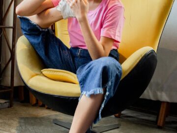 Casual young woman sitting in a yellow chair having a phone conversation indoors.