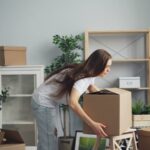A young woman with long hair arranging boxes in her new home. Ideal for moving and lifestyle stories.