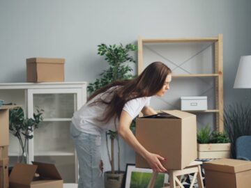 A young woman with long hair arranging boxes in her new home. Ideal for moving and lifestyle stories.