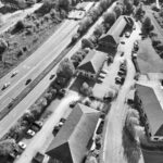 Aerial view of urban Derby, England, showcasing buildings, roads, and trees in black and white.