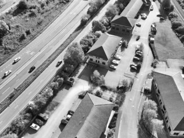 Aerial view of urban Derby, England, showcasing buildings, roads, and trees in black and white.