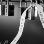 Artistic black and white image of love padlocks with a ribbon showing affection.