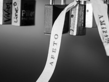Artistic black and white image of love padlocks with a ribbon showing affection.