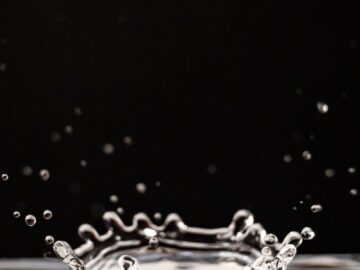 Close-up photo capturing a water droplet splash with ripples against a black background.