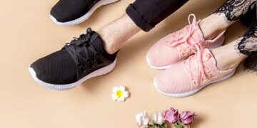 Pair of black and pink sneakers beside a bouquet of colorful flowers on a neutral background.