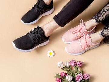 Pair of black and pink sneakers beside a bouquet of colorful flowers on a neutral background.