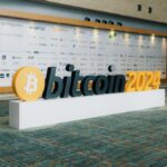 Modern entrance display for Bitcoin 2024 conference with sponsor logos in the background.