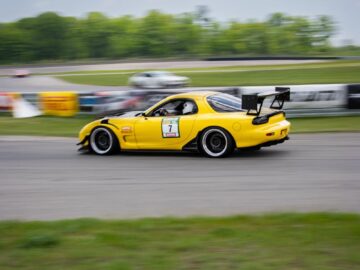 High-speed yellow sports car racing on a track with blurred motion effect.