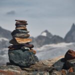 A balanced rock cairn on a rocky mountain with the Swiss Alps in the background.