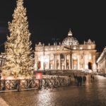 Illuminated St. Peter's Basilica and Christmas tree at night in Vatican City, showcasing festive holiday spirit.
