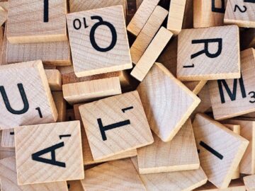 Close-up of wooden Scrabble tiles showcasing letters and numbers for word games.