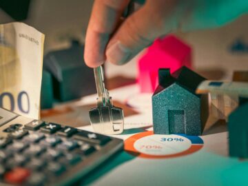 A close-up of real estate financial planning with keys, calculator, and money.