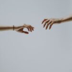 A minimalistic photo of two hands reaching out to each other against a soft, neutral background.