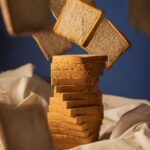 Artistic image of bread slices floating against a blue background with a rustic touch.