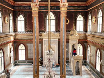 Elegant mosque interior featuring ornate designs and visitors exploring the space.