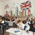 Students studying English in a classroom with British themed decor and mural.