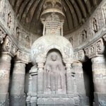 Explore the serene interior of a historic Buddhist temple showcasing intricate stone carvings and a prominent statue.