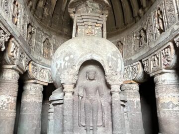 Explore the serene interior of a historic Buddhist temple showcasing intricate stone carvings and a prominent statue.