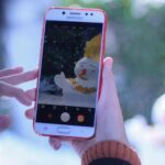 A smartphone captures an artistic photo of a snowman during winter.
