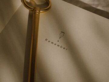 A vintage key placed on an open notebook with 'Remember' text, in soft lighting.