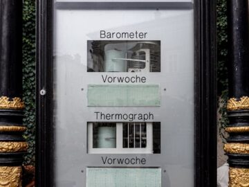 A classic weather station display featuring a barometer and thermograph in a decorative casing.