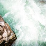 a man standing on top of a rock next to a river