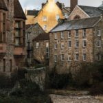 Charming view of historic stone buildings by a river in a quaint setting, showcasing architectural beauty.