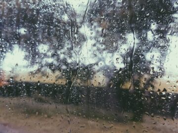 Rainy view through a window with water droplets creating an abstract pattern.