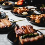 A variety of delicious Japanese yakitori skewers presented on black plates, perfect for food enthusiasts.