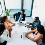 A group of professionals engaged in a business discussion around a table in a Lagos office.