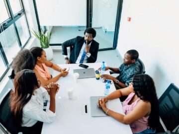 A group of professionals engaged in a business discussion around a table in a Lagos office.
