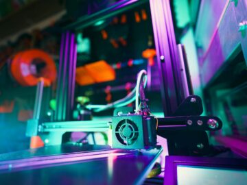 A close-up of a 3D printer in a neon-lit workshop, capturing technology and creativity.