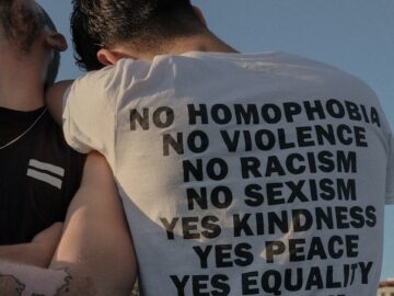 Two individuals showcasing an LGBTQ+ equality message in Istanbul for social change.