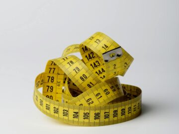 A bright yellow measuring tape coiled in loops, showcasing measurements clearly against a white background.