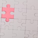 Close-up of an unfinished puzzle with a pink missing piece, highlighting emptiness.