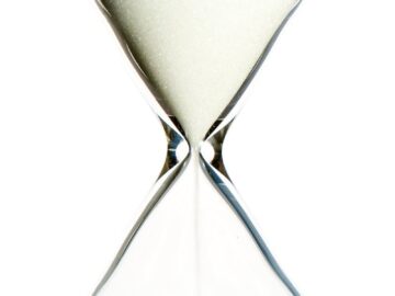 A close-up view of an elegant hourglass with flowing sand, symbolizing the passage of time.
