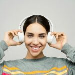 Portrait of a woman smiling while enjoying music with wireless headphones.