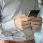 Close-up of a businessman using a smartphone, highlighting business and communication themes.