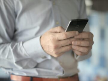 Close-up of a businessman using a smartphone, highlighting business and communication themes.