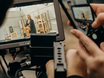 A photographer captures a video on a smartphone and monitor inside a studio setting.