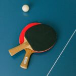 Flat lay of ping pong paddles and ball on a table tennis surface.