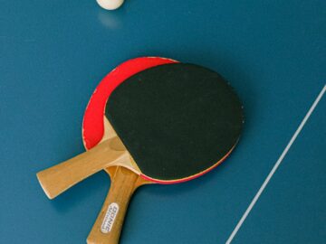 Flat lay of ping pong paddles and ball on a table tennis surface.