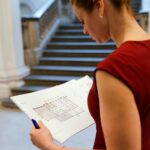 A professional woman examines an architectural floor plan in an indoor setting.