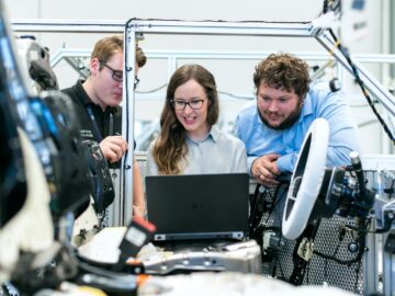 Engineers collaborating on a car project in a modern automotive workshop using advanced technology.