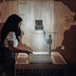 A young woman interacts with an overhead projector in a dimly lit educational setting.